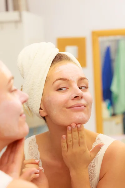 Mujer aplicando crema mascarilla en la cara en el baño —  Fotos de Stock