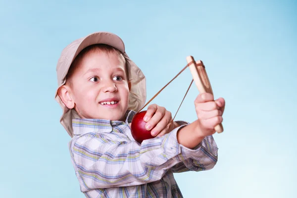 Young boy use sling shot shoot apple. — Stock Photo, Image