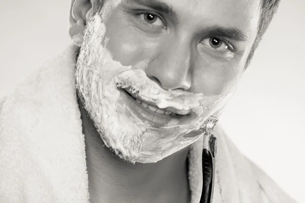 Young man shaving using razor with cream foam. — Stock Photo, Image
