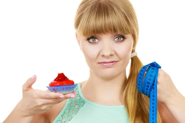 Frau hält Cupcake in der Hand und versucht der Versuchung zu widerstehen — Stockfoto