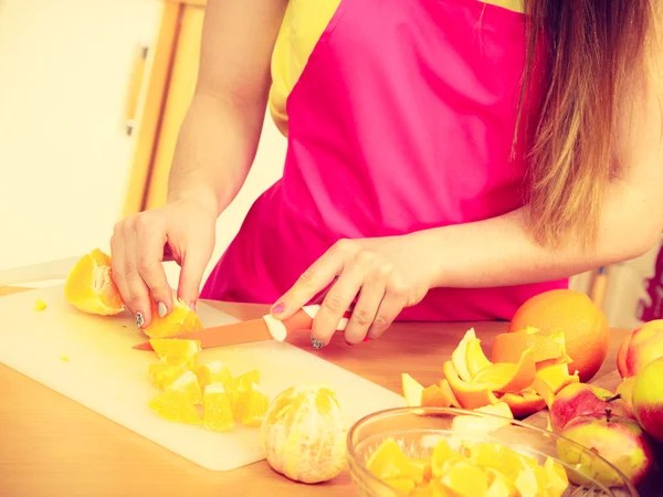 Mujer ama de casa en cocina corte de frutas naranja — Foto de Stock