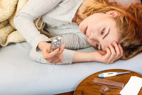 Una mujer enferma en la cama tomando pastillas. Tratamiento de salud . — Foto de Stock