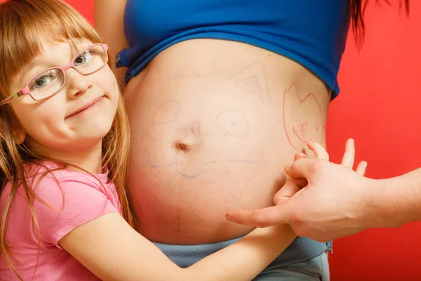 Těhotná žena s dcerou malujte mámino břicho — Stock fotografie