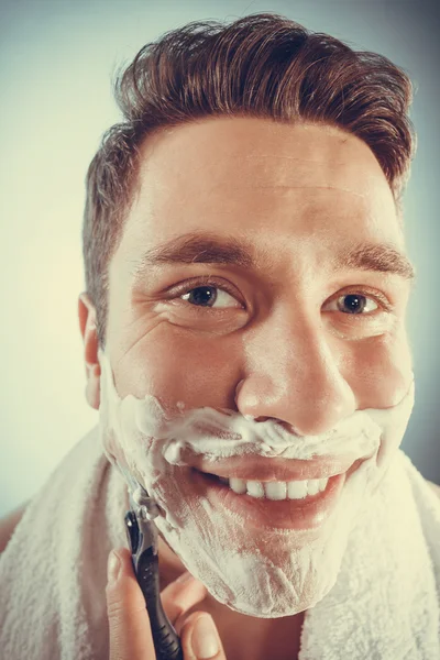 Happy man shaving using razor with cream foam. — Stock Photo, Image