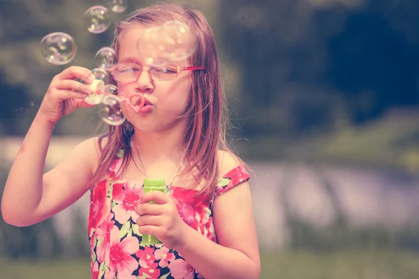 Lilla flickan barnet blåser såpbubblor utomhus. — Stockfoto
