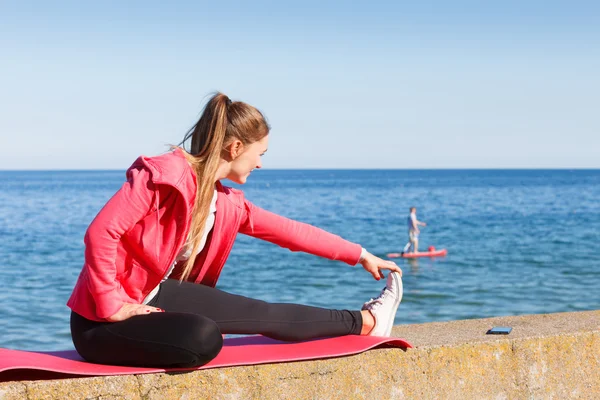 Woman doing sports exercises outdoors by seaside — Stock Photo, Image