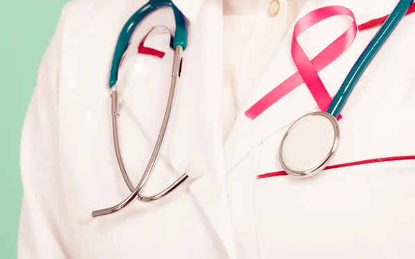 Pink ribbon with stethoscope on medical uniform. — Stock Photo, Image