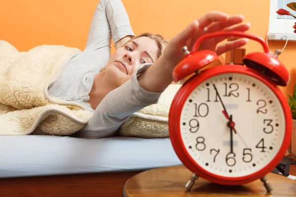 Woman waking up turning off alarm clock in morning — Stock Photo, Image