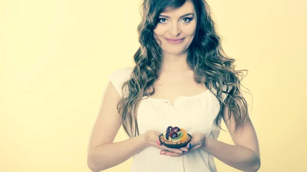 Smiling cute woman holds fruit cake in hand — Stock Photo, Image