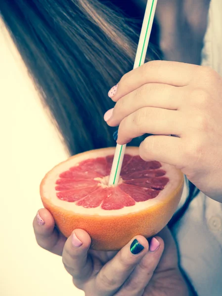 Woman holds grapefruit drinking juice from fruit — Stock Photo, Image