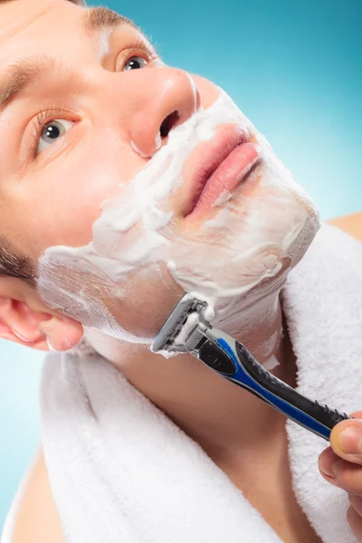 Jonge man scheren scheermes gebruiken met crème schuim. — Stockfoto