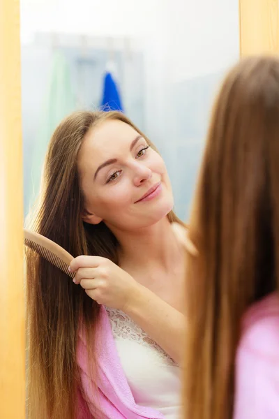 Frau kämmt ihre langen Haare im Badezimmer — Stockfoto