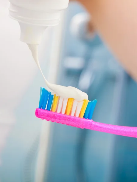 Woman hands putting toothpaste on toothbrush — Stock Photo, Image