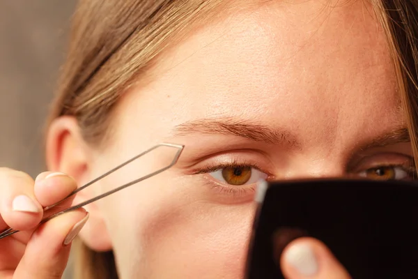 Woman tweezing eyebrows depilating with tweezers — Stock Photo, Image