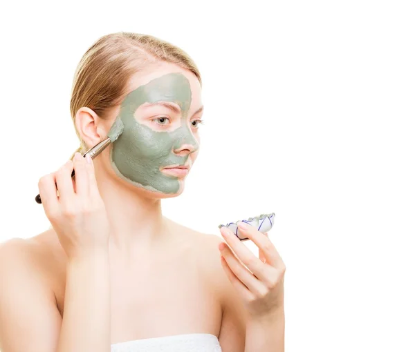 Chica aplicando mascarilla de arcilla facial en su cara —  Fotos de Stock