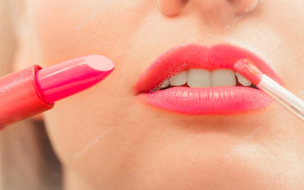 Woman applying lipstick with brush on lips. Makeup Stock Photo by