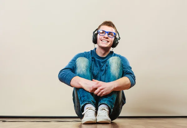 Ung man med hörlurar sittande på golvet — Stockfoto