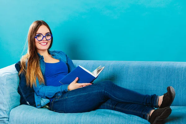 Woman sitting on couch reading book at home — Stock Photo, Image