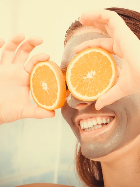 Wanita dengan topeng wajah lumpur memegang irisan oranye — Stok Foto