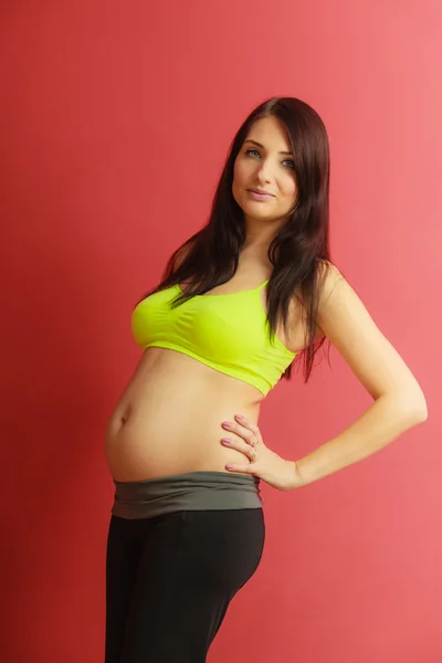 Långt hår passar gravid kvinna på rött — Stockfoto