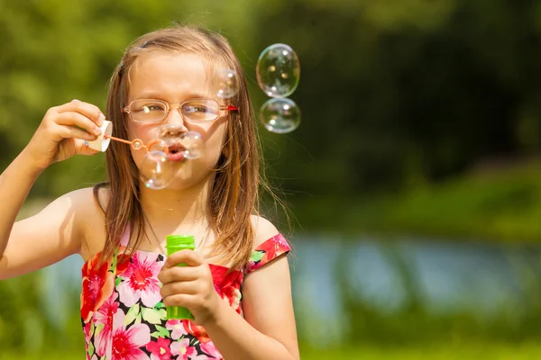 Lilla flickan barnet blåser såpbubblor utomhus. — Stockfoto