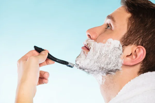 Genç adam ustura ile krem köpük kullanarak tıraş. — Stok fotoğraf