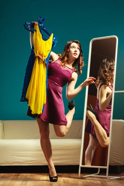 Mulher comprador prende cabides com roupas olhando no espelho — Fotografia de Stock