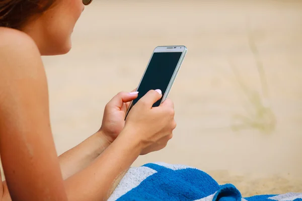 Vrouw op het strand sms 'en op smartphone. — Stockfoto