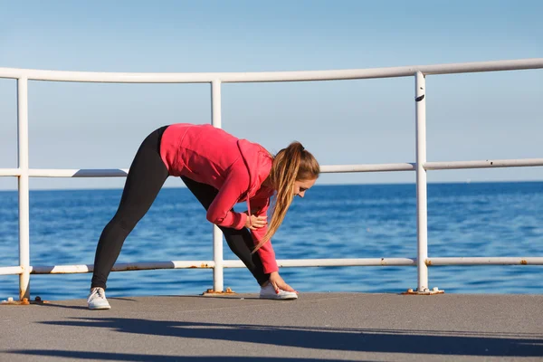 Mulher fazendo exercícios esportivos ao ar livre à beira-mar — Fotografia de Stock