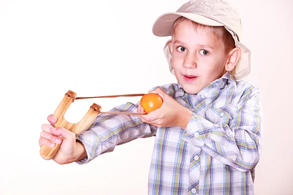 Ung pojke använda sling skott skjuta mandarine. — Stockfoto