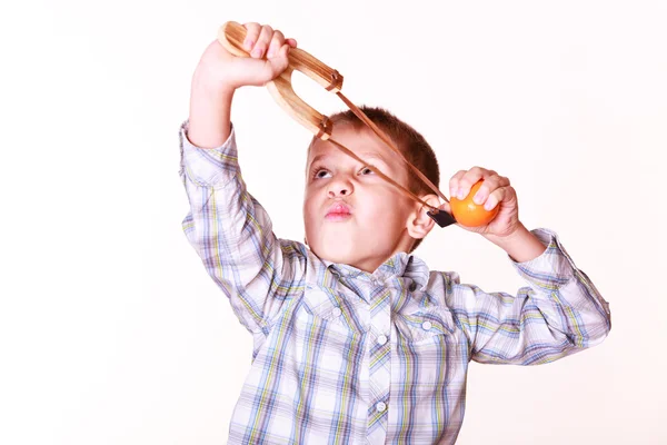 Mladík použitím praku výstřel natáčení mandarine. — Stock fotografie