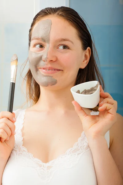 Woman applying mud facial mask
