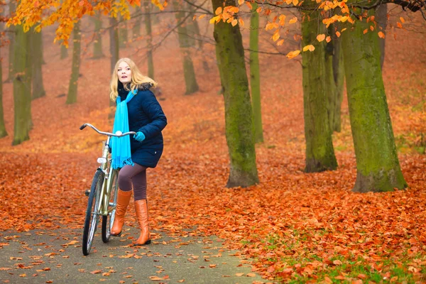 アクティブな女性秋の公園で自転車に乗る. — ストック写真