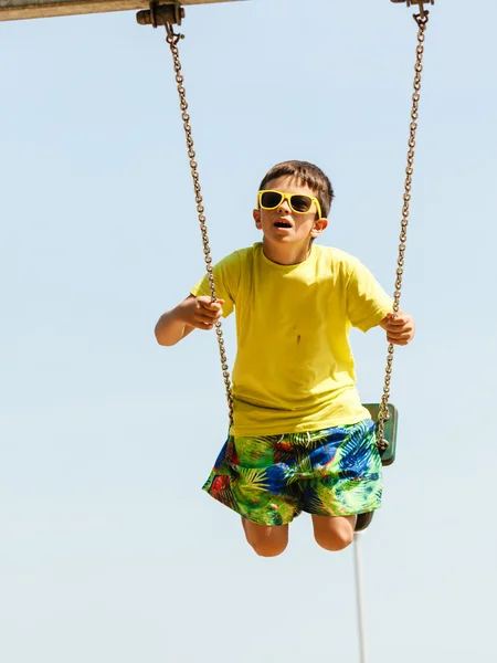 Ragazzo che gioca oscillando da swing-set. — Foto Stock