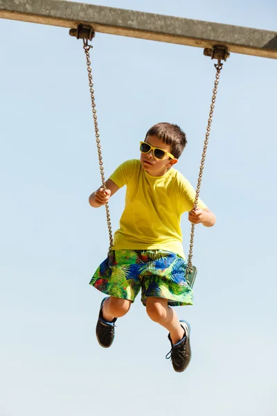 Pojken spelar svängande av swing-set. — Stockfoto
