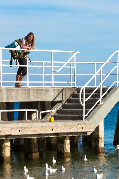 Man wandelaar met rugzak op pier, landschap van zee — Stockfoto