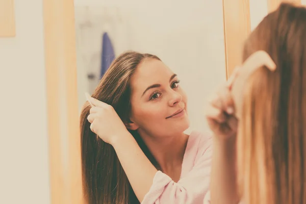 Woman combing her long hair in bathroom — Stock Photo, Image