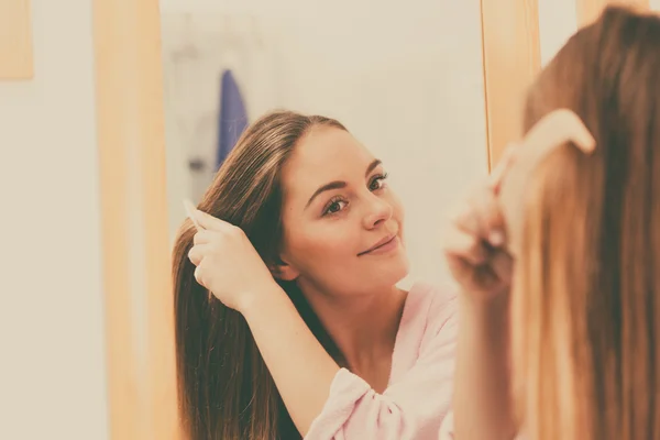 Frau kämmt ihre langen Haare im Badezimmer — Stockfoto