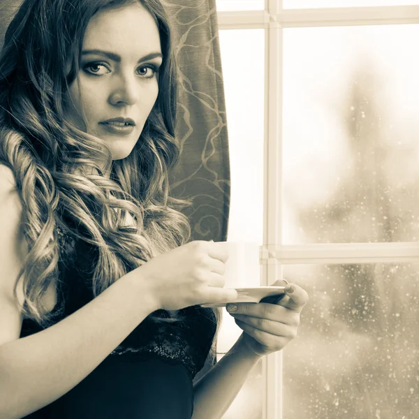 Sensual woman drinking hot coffee beverage at home