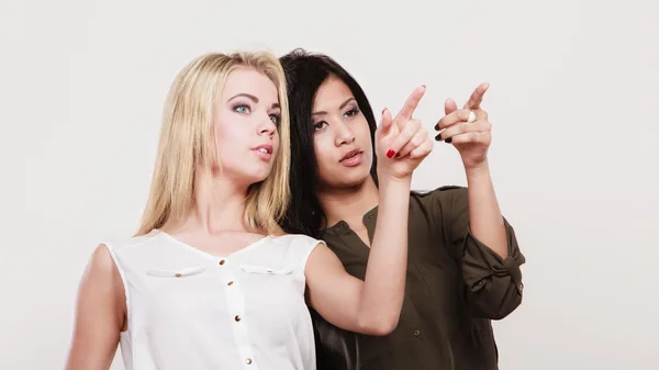Zwei Modefrauen, die mit dem Zeigefinger zeigen — Stockfoto