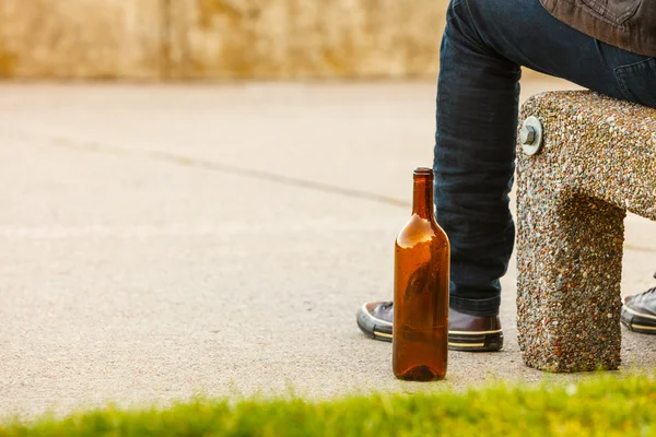 Man depressed with wine bottle sitting on bench outdoor — Stock Photo, Image