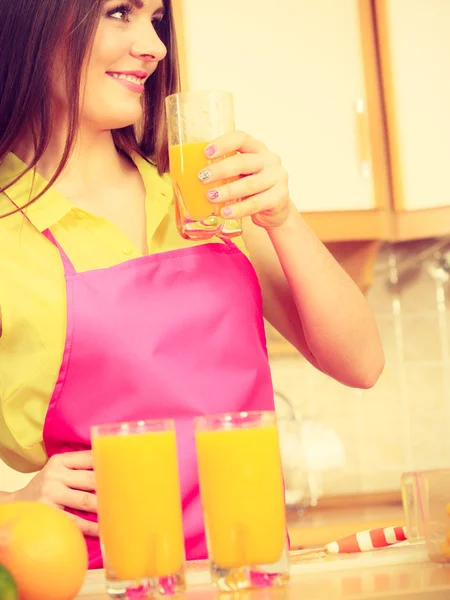 Mulher na cozinha beber suco de laranja fresco — Fotografia de Stock