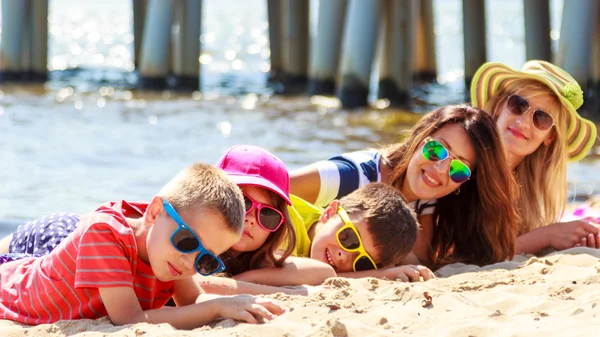 Szczęśliwa rodzina kobiety dzieci opalając się na plaży. — Zdjęcie stockowe