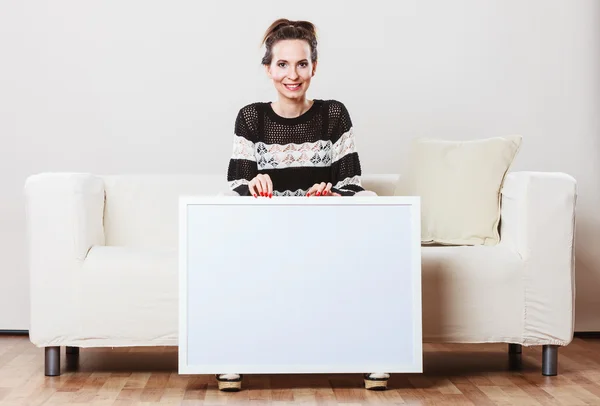 Mujer en sofá sosteniendo tablero de presentación en blanco. — Foto de Stock