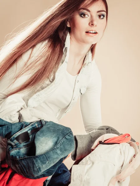Junge Frau hält Stapel Kleidungsstücke. — Stockfoto