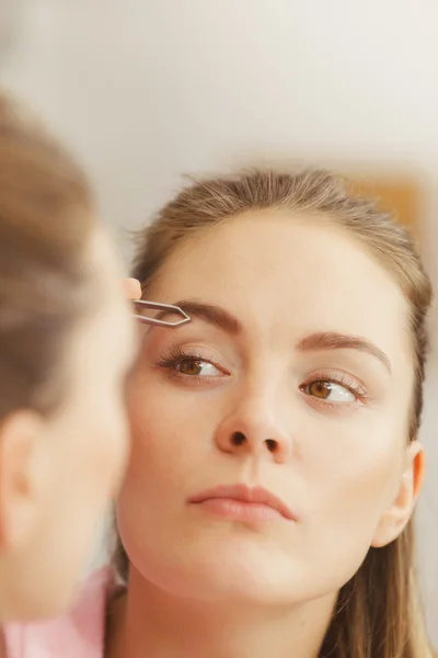 Mujer pincelando cejas arrancando con pinzas —  Fotos de Stock