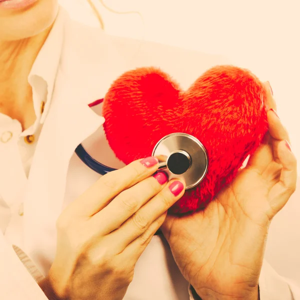 Médico con estetoscopio examinando el corazón rojo . — Foto de Stock