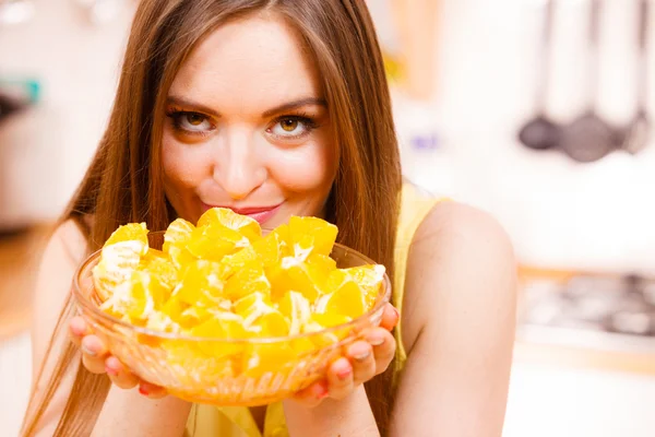 Woman holds bowl full of sliced orange fruits — Stock Photo, Image