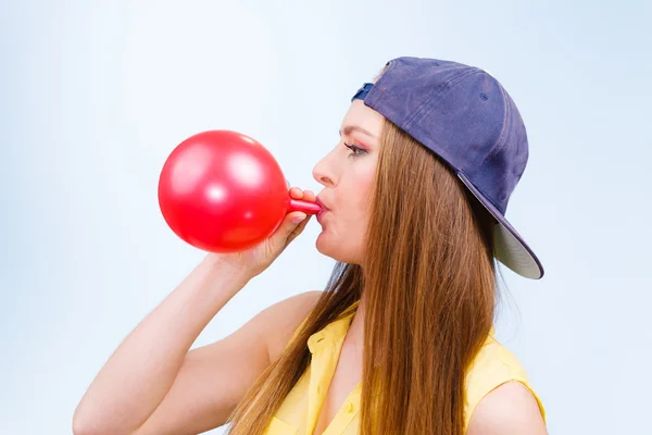 Vrouwelijke tiener oppompen rode ballon. — Stockfoto