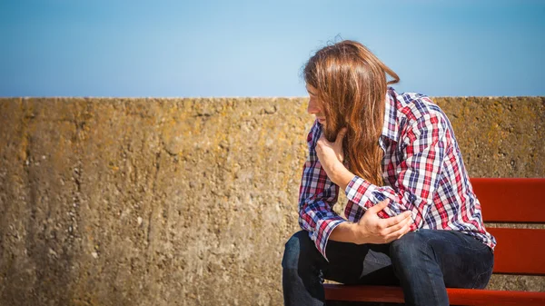 Man långt hår sitter på bänken utomhus — Stockfoto